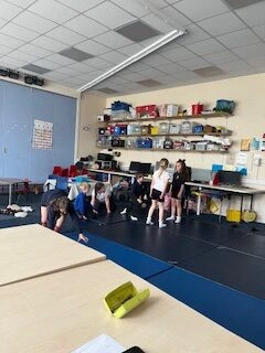 Children participating in indoor physical exercises and floor activities under staff supervision at the Pitmedden Primary School breakfast and after school club in Ellon, Aberdeenshire.