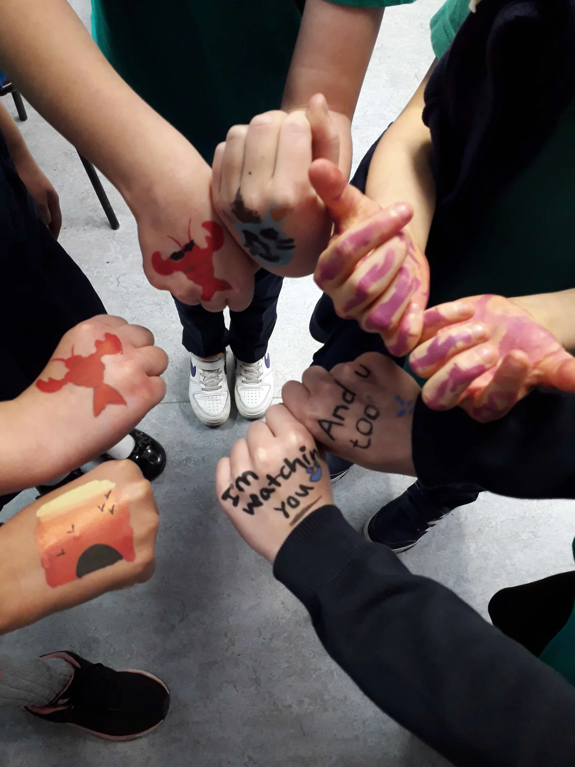 Close-up of children's hands with colorful temporary ink drawings and paintings during a creative session at St Joseph’s Primary School after school club in Aberdeen.